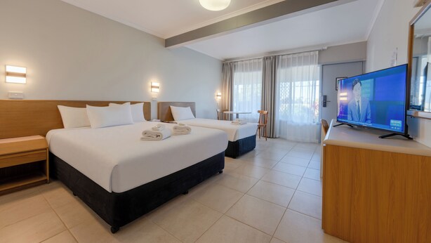 Una habitación de hotel con una cama grande, mesitas de noche, un televisor y un escritorio.
