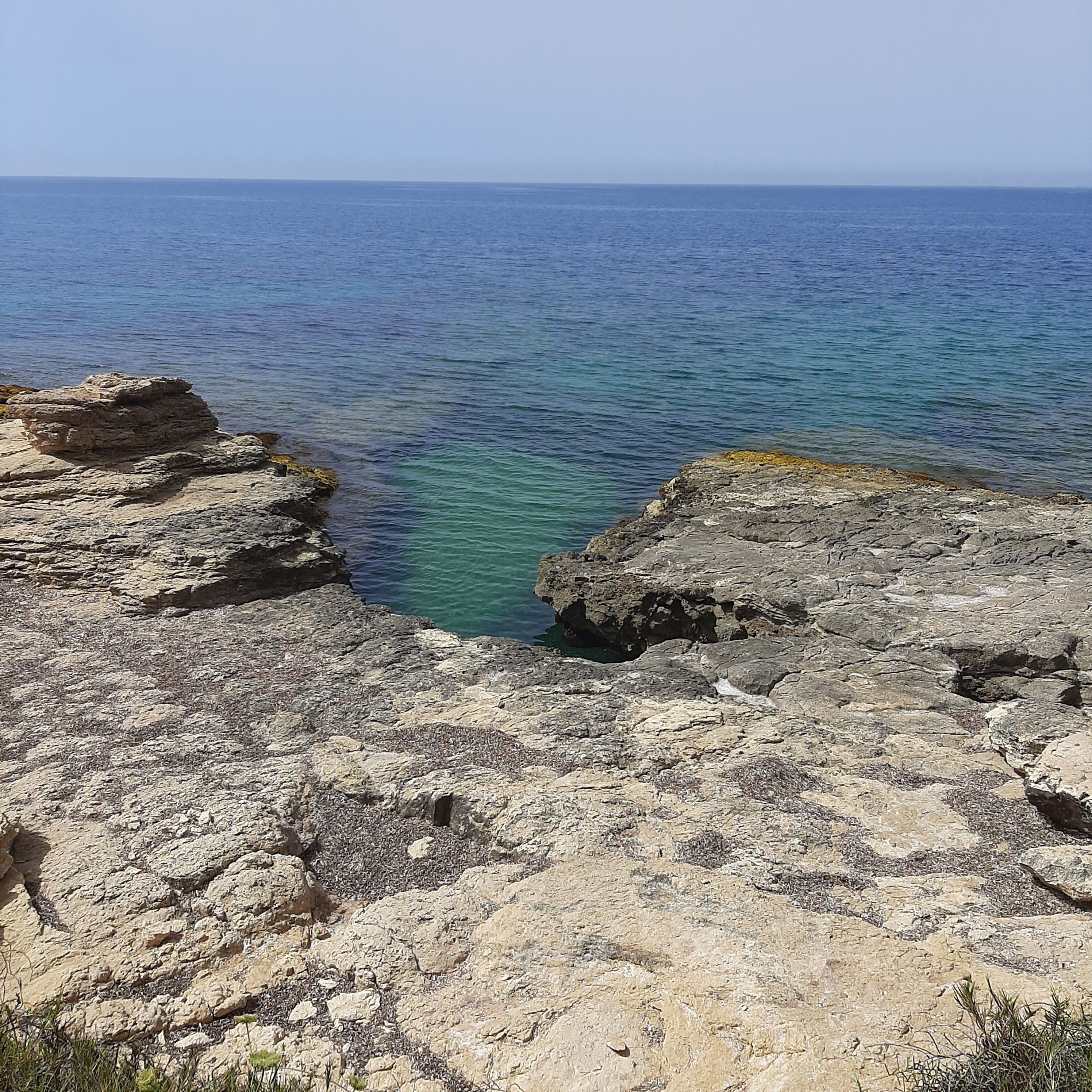 Costa rocosa con mar azul cristalino y vista al horizonte.