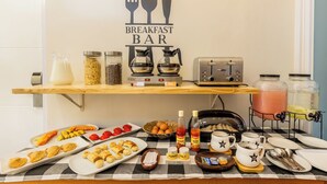 A breakfast bar with a coffee machine, tea maker, and various breakfast items like pastries and condiments. - Omah Manis Taman Siswa (Yogyakarta)