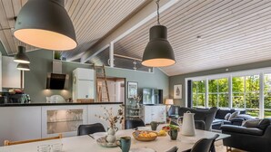 A modern kitchen with a dining area, large windows, and a loft-style ceiling.
