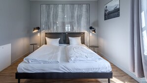 Quarto moderno com uma cama grande, duas mesas de cabeceira e uma obra de arte na parede.