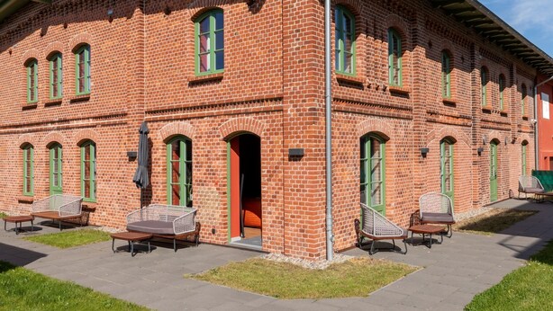 Um edifício de tijolos com várias janelas e uma área de estar coberta ao ar livre.