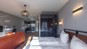 Una habitación de hotel moderna con una cama grande, un sofá, una zona de cocina y vistas a la ciudad.