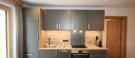 Una cocina moderna con armarios grises, encimera de madera y horno integrado.