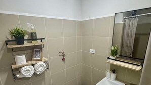A small bathroom with a toilet, sink, and shelves with towels and toiletries. - Stunning skyline views in Makati (Makati)
