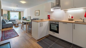Eine moderne Küche mit weißen Schränken, einem eingebauten Backofen und einer roten Kaffeemaschine.