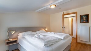 Ein ordentlich bezogenes Bett mit weißen Leinen und Handtüchern, eine Nachttischlampe und ein kleiner Nachttisch.