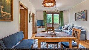 A modern living room with a dining area, a television, and a sofa. - Nice apartment for 5 people with WIFI, balcony and panoramic view (Frauenstein)