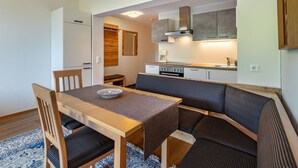A compact kitchen with a dining area, including a table with chairs and a bench. - Nice apartment for 5 people with WIFI, balcony and panoramic view (Frauenstein)