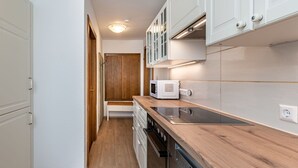 A narrow kitchen with white cabinets, a wooden countertop, and a built-in microwave. - Lovely apartment for 6 people with WIFI, TV, terrace and panoramic view (Frauenstein)