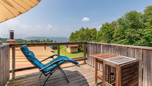 A wooden deck with a blue lounge chair and a small table, overlooking a forested area and distant mountains. - Lovely apartment for 6 people with WIFI, TV, terrace and panoramic view (Frauenstein)