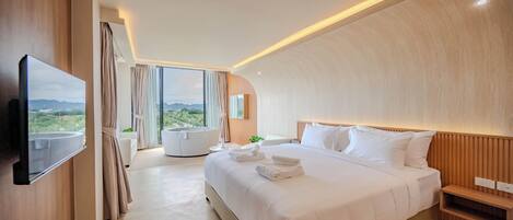 Habitación de hotel moderna con una cama grande, un televisor de pantalla plana montado en la pared, vistas al exterior y un diseño de techo curvo.