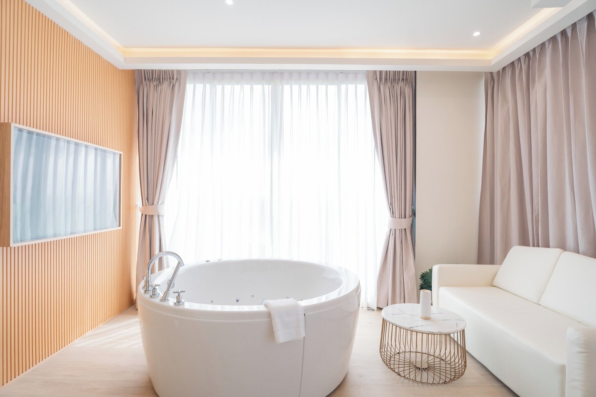 A modern bathroom with a freestanding bathtub, a white sofa, and a small round table.