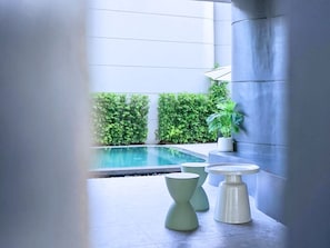 A modern indoor pool area with a clear view of the pool, surrounded by greenery and minimalist furniture. - G9 Hotel Kanchanaburi (Kanchanaburi)