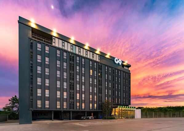 A modern hotel building with a prominent 'G9' sign, large windows, and a parking area. - G9 Hotel Kanchanaburi (Kanchanaburi)