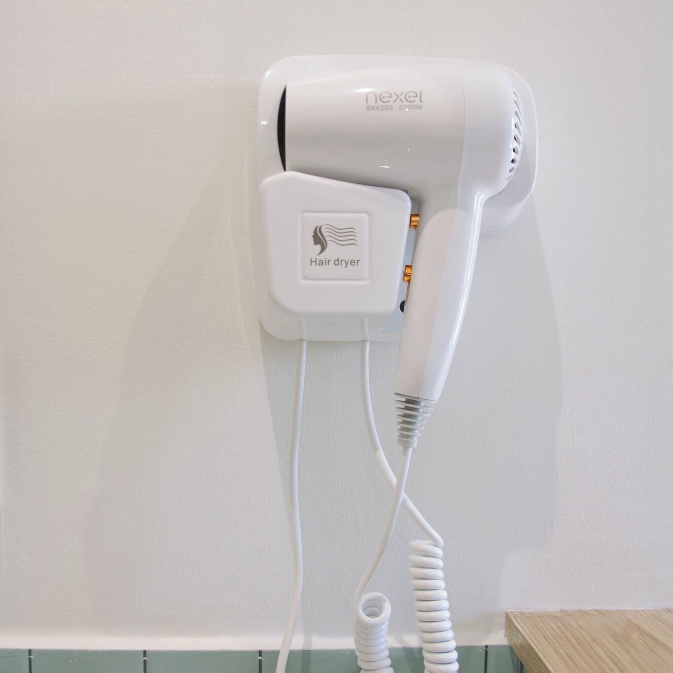 A hair dryer mounted on a wall with a cord.