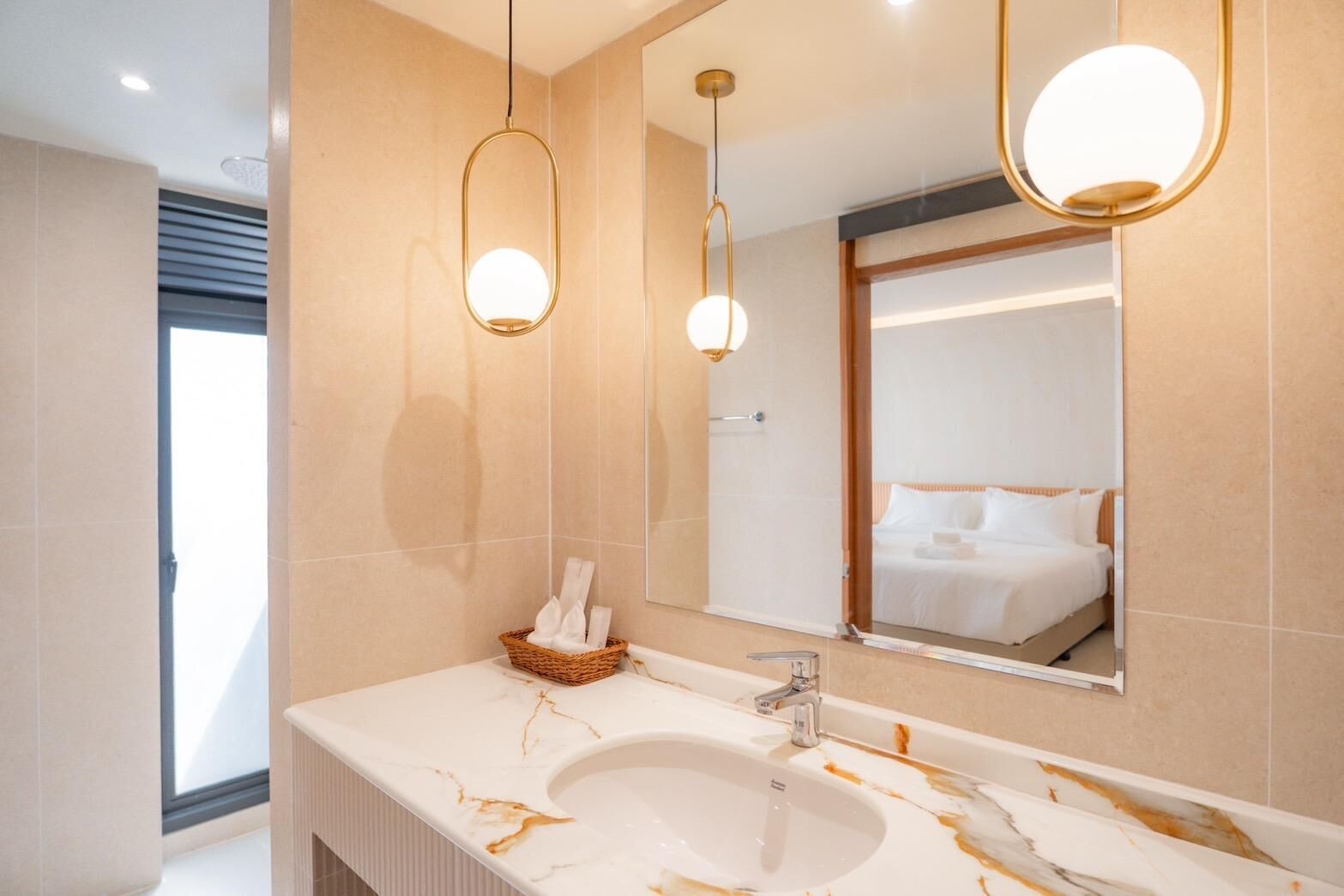 A modern bathroom with a marble sink, a large mirror, and two pendant lights.