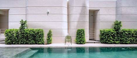 A modern building with a pool, featuring a clean, minimalist design with geometric shapes and a flat roof.