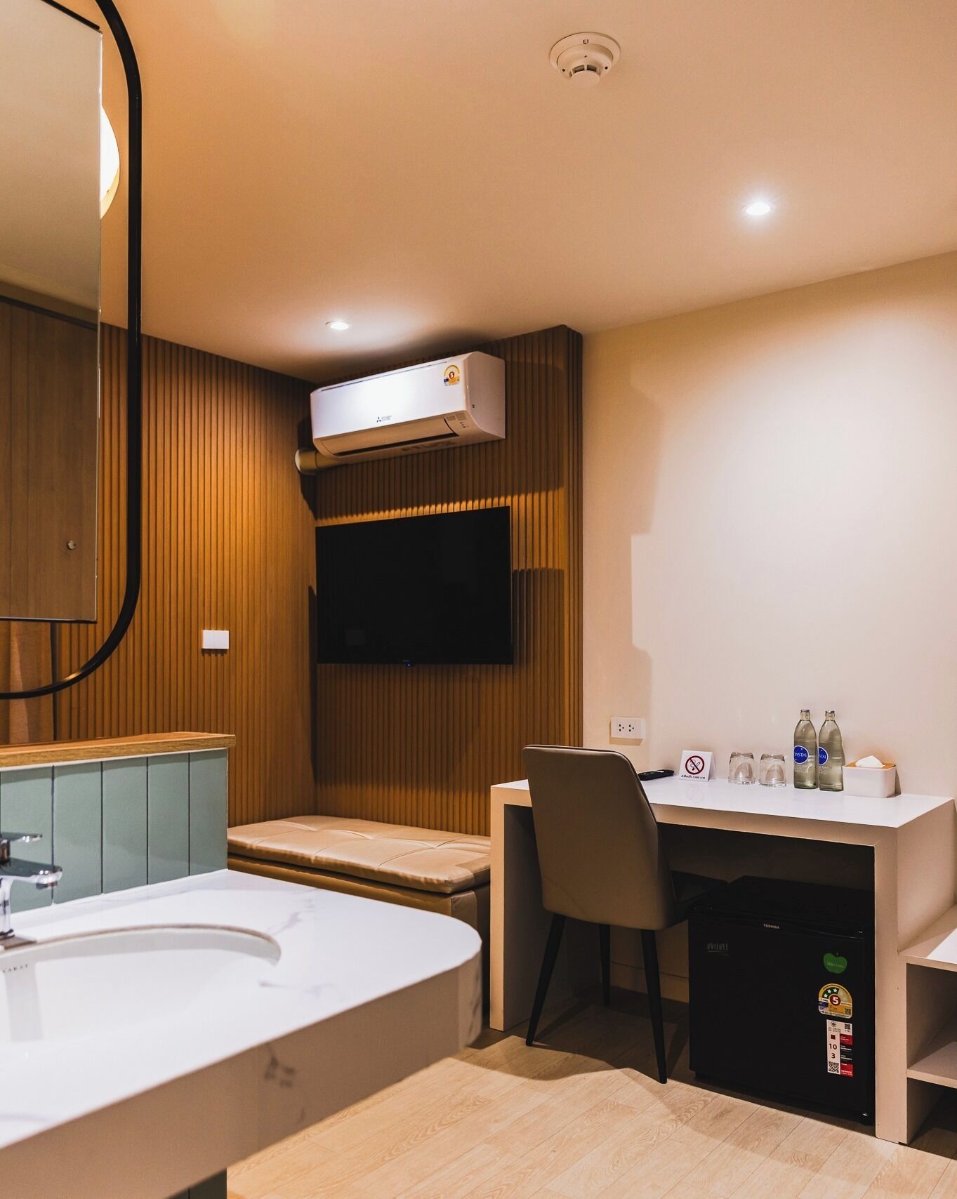 Ett modernt hotellrum med en stor säng, ett skrivbord med en stol, en tv och en minibar.