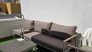 Un área de estar al aire libre con un sofá, sillones y una mesa.