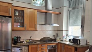 Una cocina compacta con armarios de madera, horno empotrado, lavavajillas y microondas.