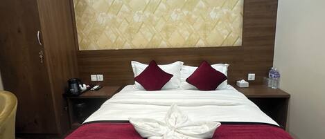 A hotel room with a neatly made bed, a wooden headboard, and a nightstand with a water bottle and tissues.