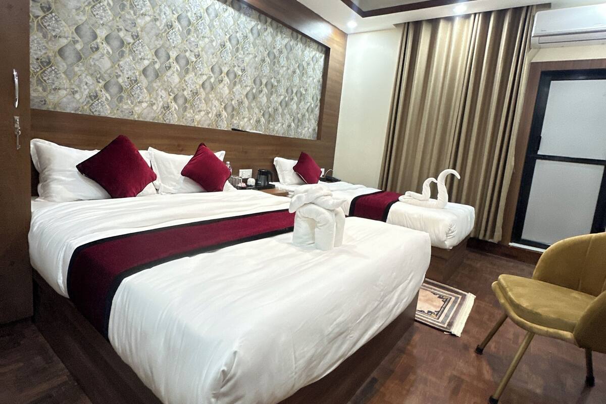 A hotel room with a large bed, a smaller bed, a chair, and a decorative ceiling.