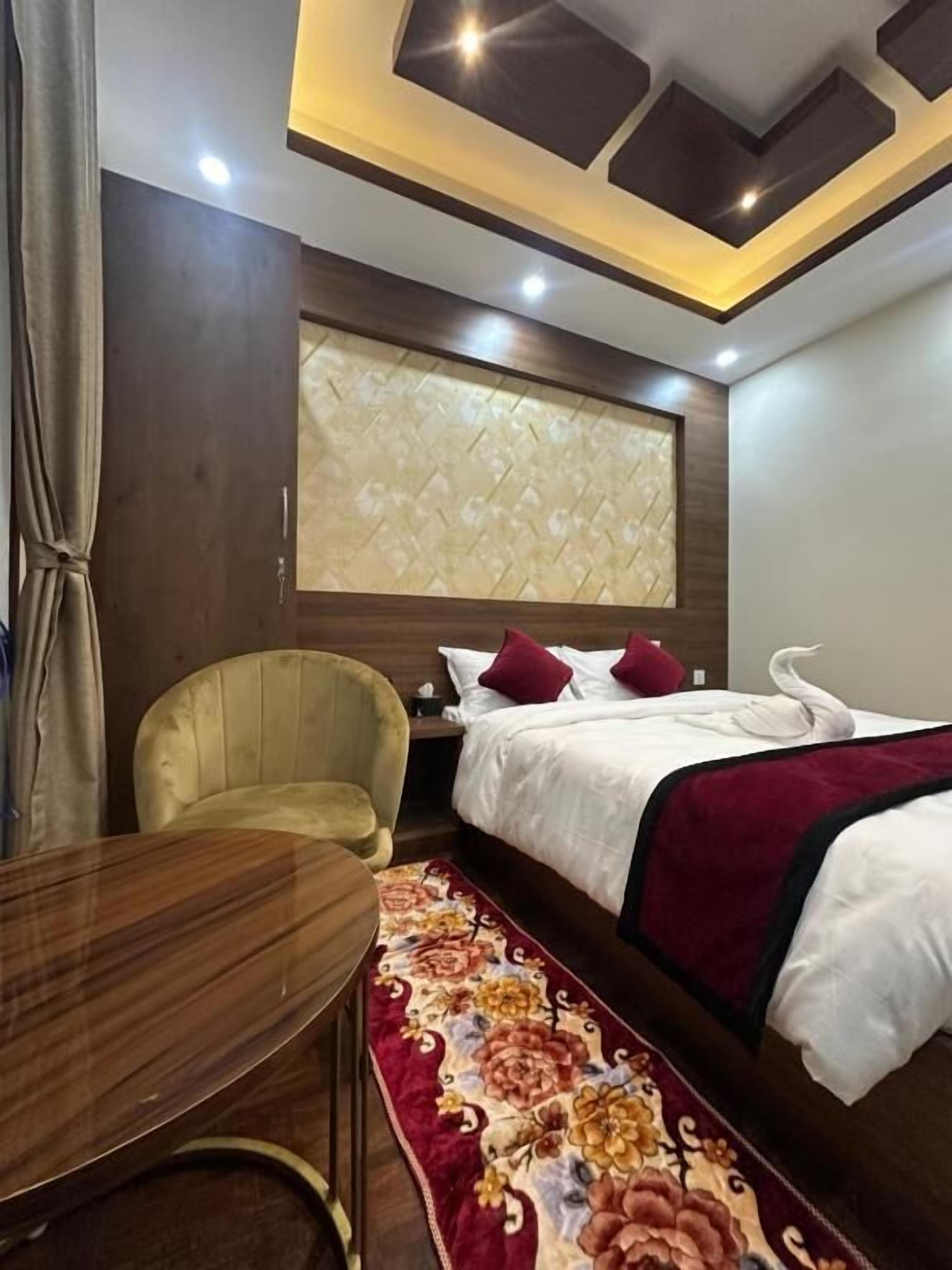 Ein Hotelzimmer mit Bett, einem Sessel, einem kleinen Tisch und einem dekorativen Teppich.