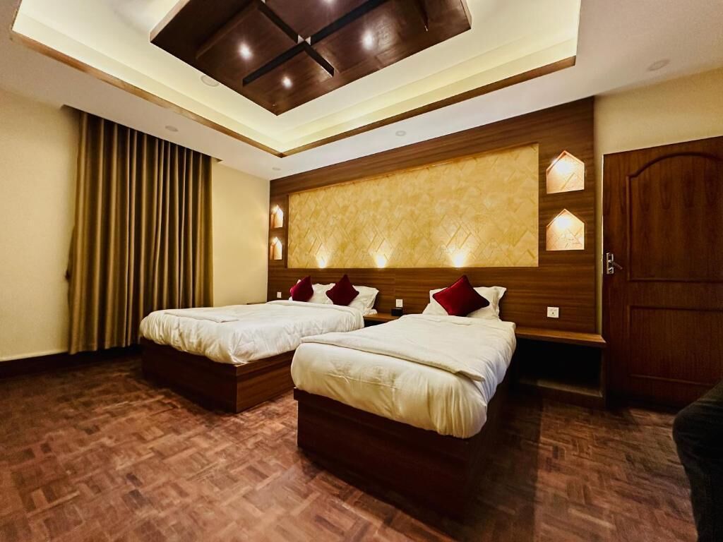 Quarto de hotel com duas camas, cabeceira de madeira e luminária no teto.