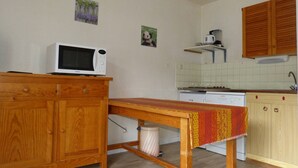 A compact kitchen with wooden cabinets, a microwave, a stove, and a sink.
