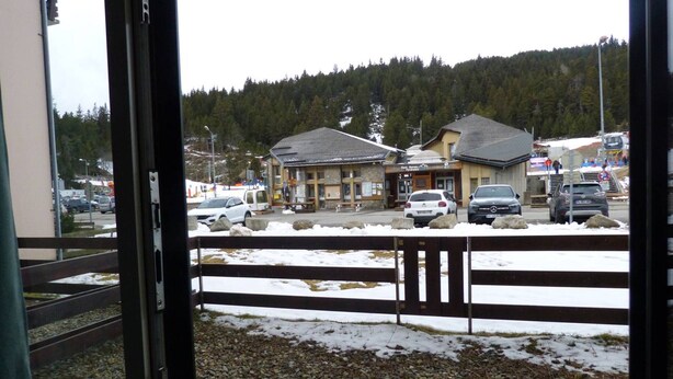 A view of a building with a parking area in front, surrounded by a wooden fence.