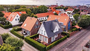 A residential area with houses featuring red-tiled roofs and white-framed windows. - Ferienhaus Strandhafer (Wangerooge)