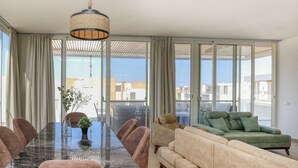 Ett modernt vardagsrum med en matplats med glasbord, en soffa och en hängande lampa.