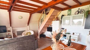 Ein großzügiger Wohnbereich mit einem Holzesstisch, einem grauen Sofa und einer Treppe, die in eine obere Etage führt.