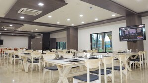 A conference room with tables and chairs, a flat-screen TV, and a ceiling with recessed lighting. - Praveg Rezort Silvassa (Silvassa)