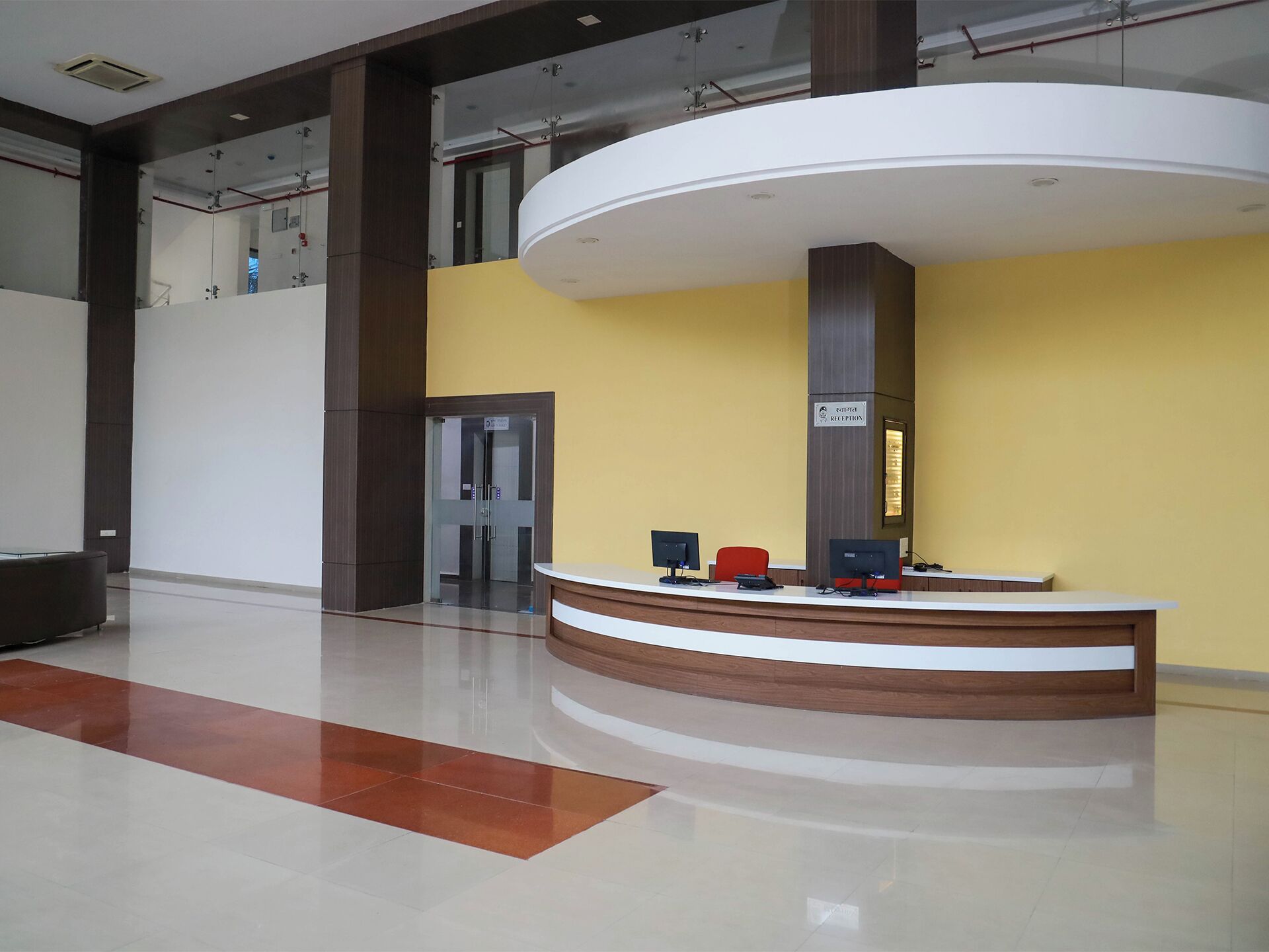 A reception area with a curved desk, computers, and a sign indicating a reception desk.