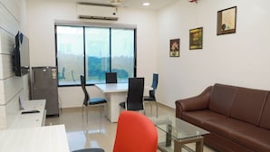 A modern office space with a glass table, leather sofa, and a large window offering a view of the city. - Praveg Rezort Silvassa (Silvassa)