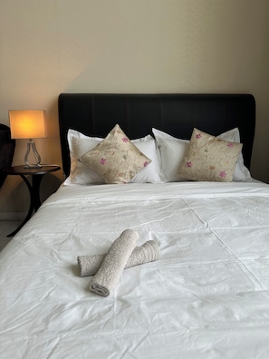 Restful retreat with a neatly made bed, featuring a white duvet and decorative pillows.