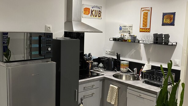 A modern kitchen with a built-in microwave, stove, and dishwasher. There are signs on the wall indicating a coffee shop and a bakery.