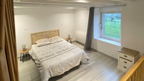 A bedroom with a bed, bedside tables, a window with a view, and a wooden staircase.