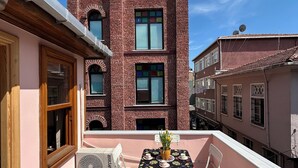 Ein zweistöckiges Gebäude mit Backsteinfassade, großen Fenstern und einem Balkon mit Tisch und Stühlen.