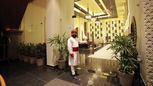 Un hall d’hôtel avec un comptoir d’accueil, des plantes en pot et un lustre moderne.