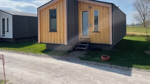 A modern, single-story wooden cabin with a large sliding door and a small set of steps leading to the entrance. - MoJo's Tiny House on the Elbe (Bleckede)