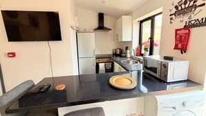 A compact kitchen with a flat-screen TV, a microwave, a washing machine, and a sink. - 526A Farnham Rd  (Slough)