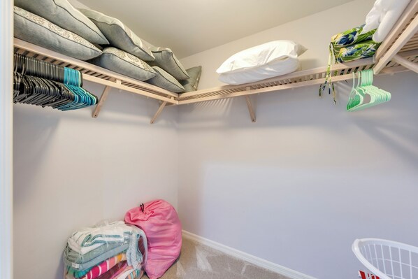 A closet with shelves for hanging clothes, a bench with folded clothes, and a storage bin.