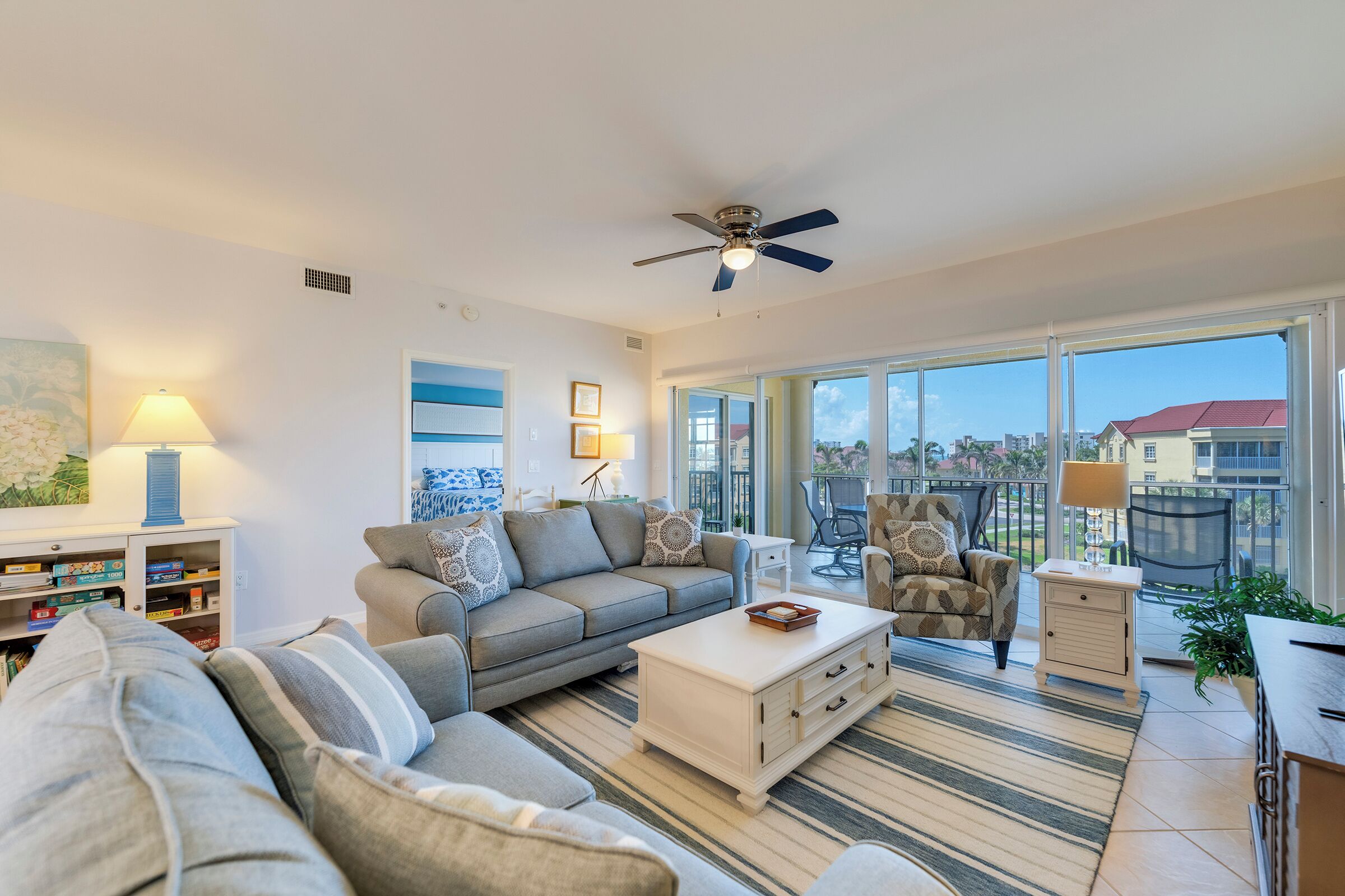 A spacious living room with a sofa, armchairs, a coffee table, and a ceiling fan.