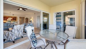 Un amplio salón con mesa de vidrio, asientos cómodos y vista al área de cocina y comedor.