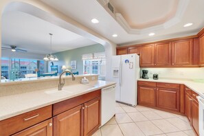 A modern kitchen with wooden cabinets, a white refrigerator, and a built-in dishwasher.