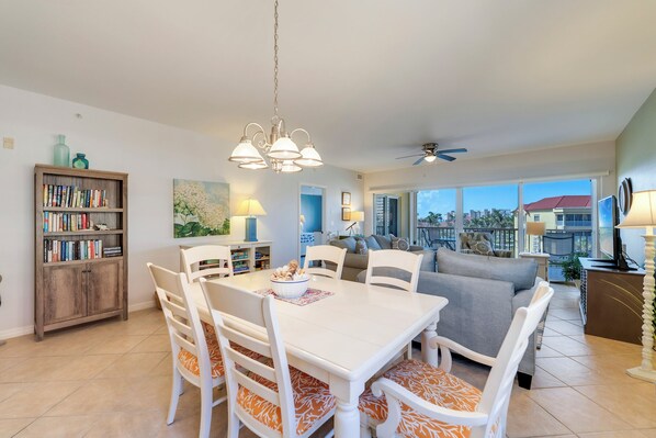A spacious living area with a dining table, chairs, a sofa, and a bookshelf.