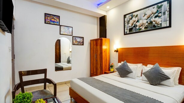 Una habitación de hotel con cama, cabecera de madera, espejo y obras de arte en las paredes.